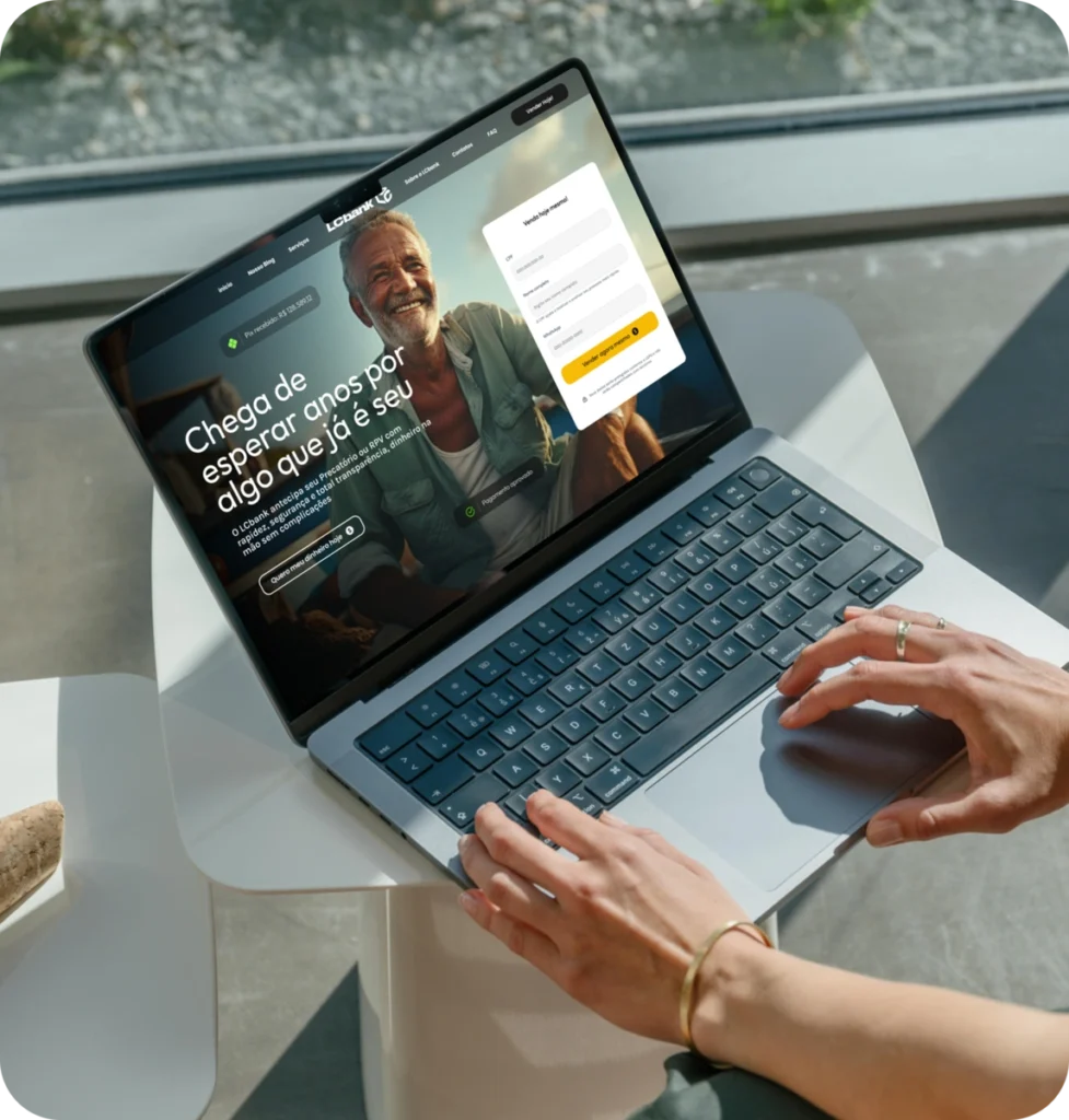 Laptop exibindo site do LCbank com homem sorrindo e formulário de login.